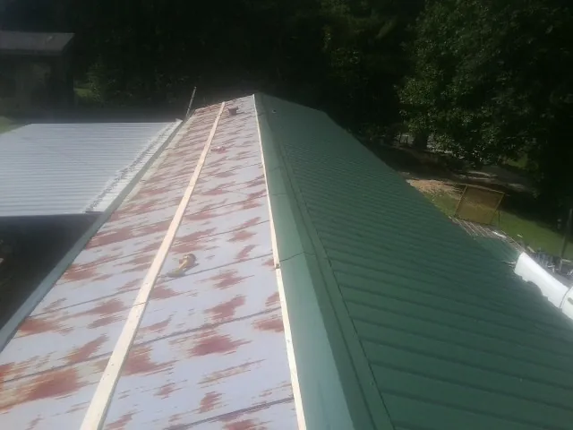 Old rusted panels beside newly installed green metal roofing — Wind Damage Roof Repair by Roofing Brothers in South Beloit
