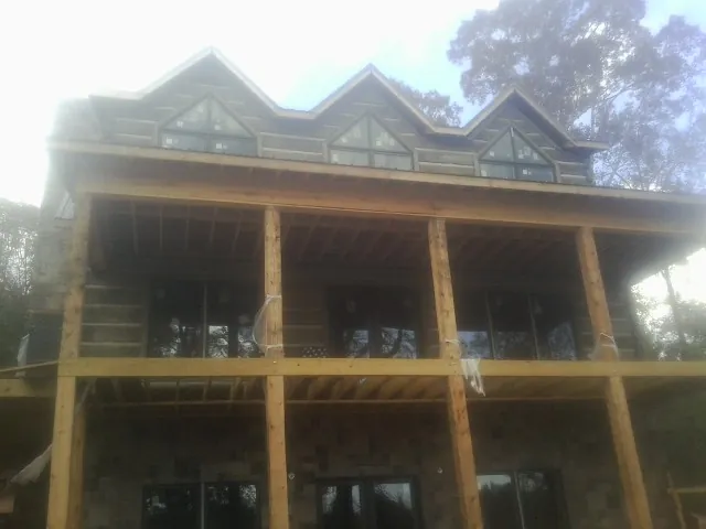 Dormers and porch framing on a large log home under construction — Roof Coating work by our crew in South Beloit