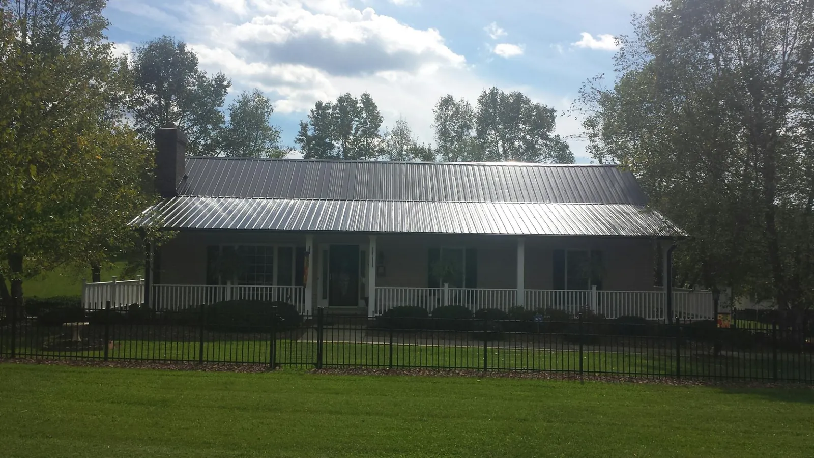 Gray metal roof on a brick ranch with a full width front porch — Gutter Guard Installation work by our crew in South Beloit