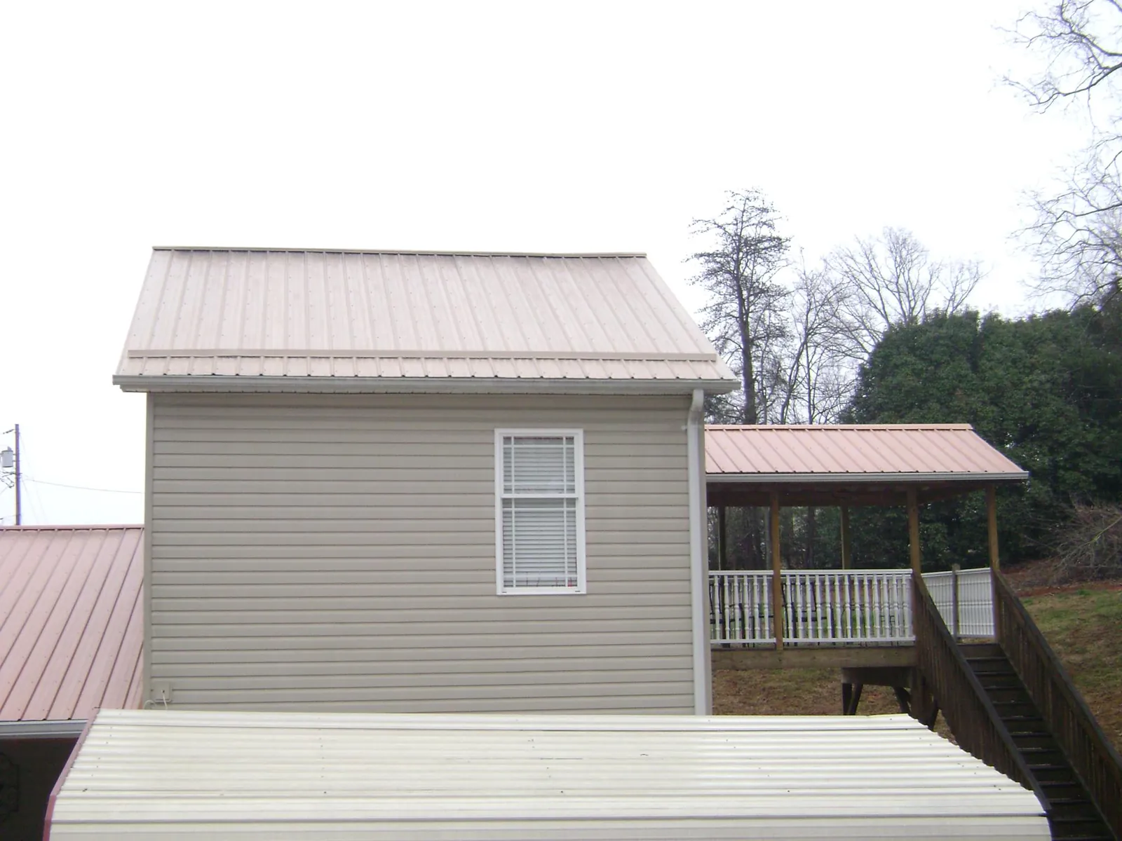 Tan metal roofs on a two story addition and attached porch, from a Roof Replacement job in South Beloit