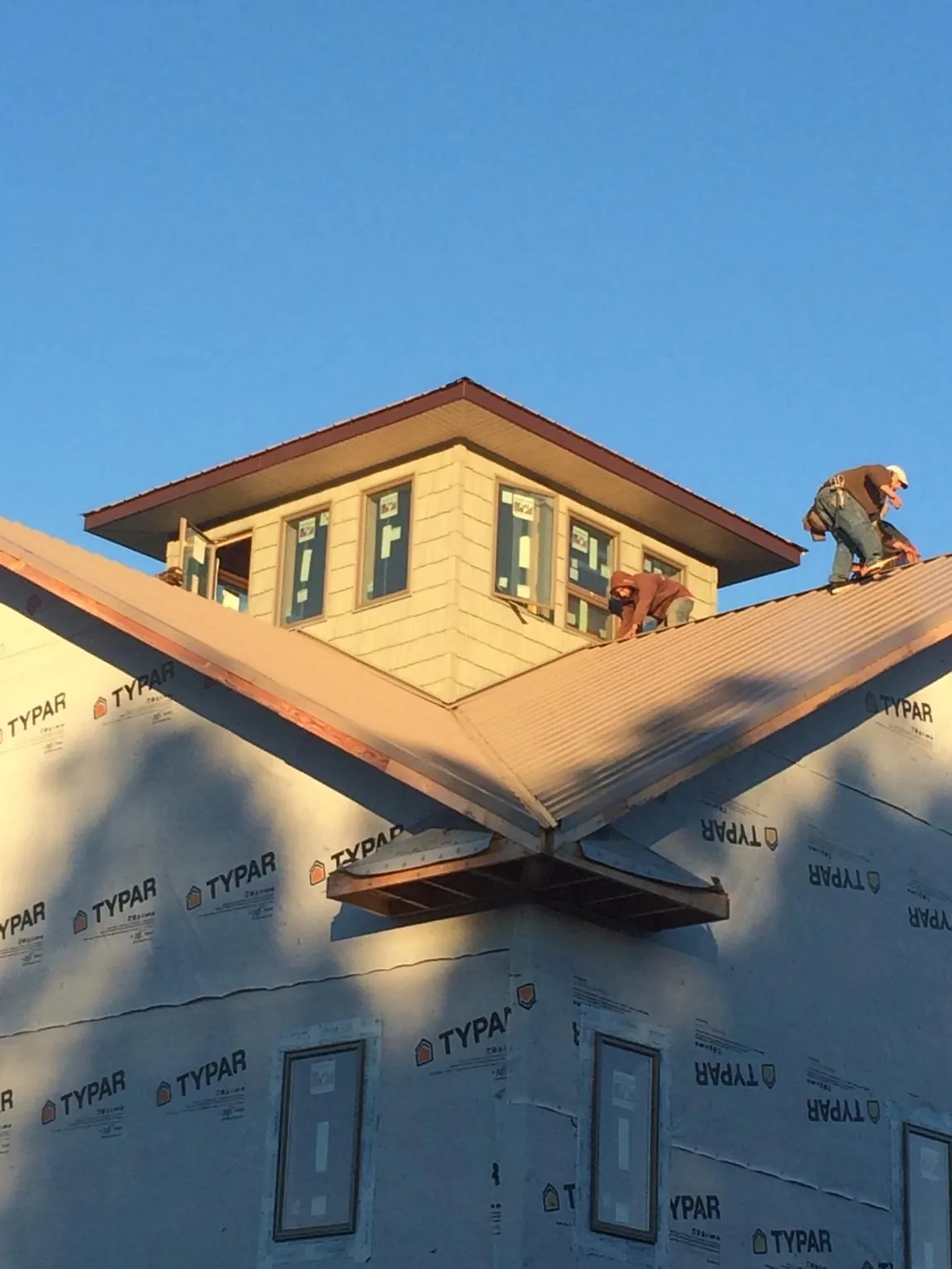 Roofers working around a rooftop cupola on a new metal roof at sunset — Roof Waterproofing in South Beloit by Roofing Brothers